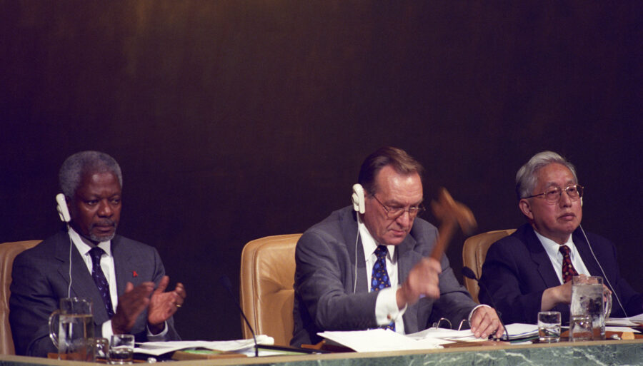 Three men sitting at a meeting table with headsets on.