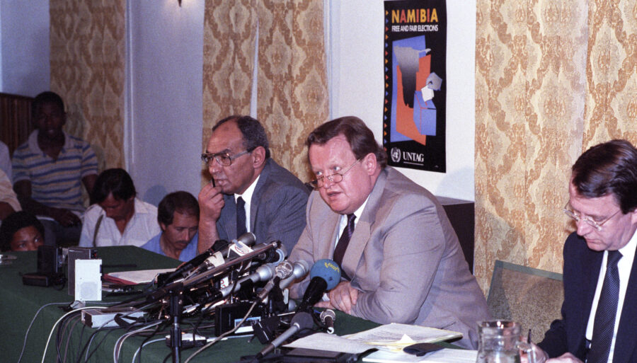 Martti Ahtisaari and several others sitting at a table behind microphones.