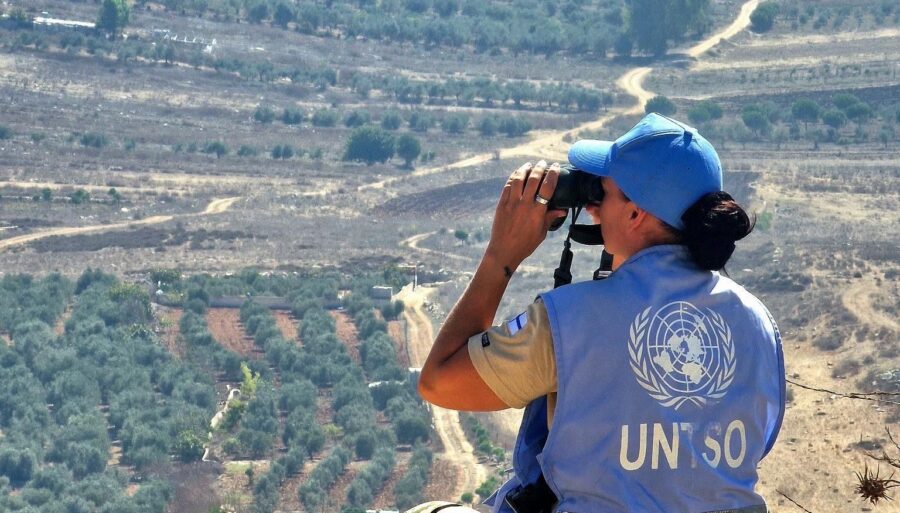 A peacekeeper scanning the horizon through binoculars.
