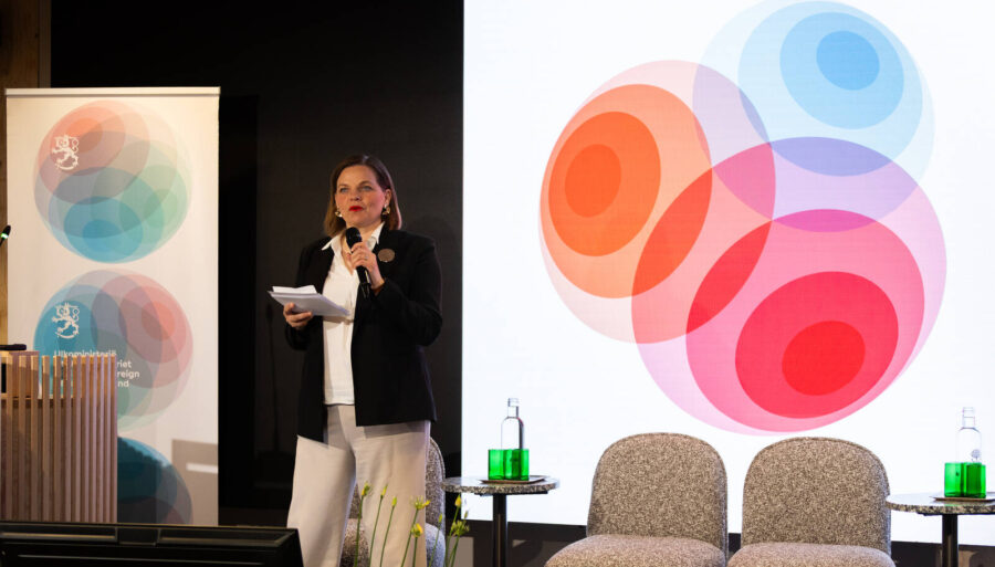 A speaker on stage, with a colorful visual element in the background.