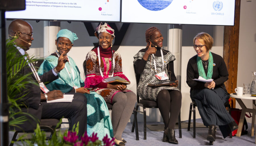 Smiling participants seated on a stage in a panel discussion format.