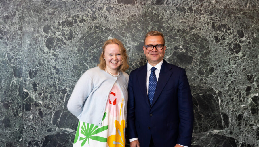Prime Minister Petteri Orpo standing next to the Youth Delegate, looking at the camera.