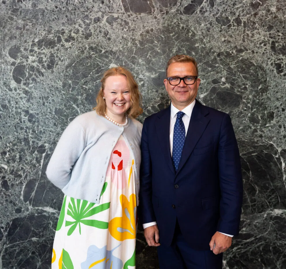 Prime Minister Petteri Orpo standing next to the Youth Delegate, looking at the camera.
