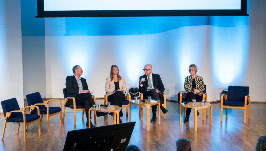 Four people participating in a panel discussion on stage.