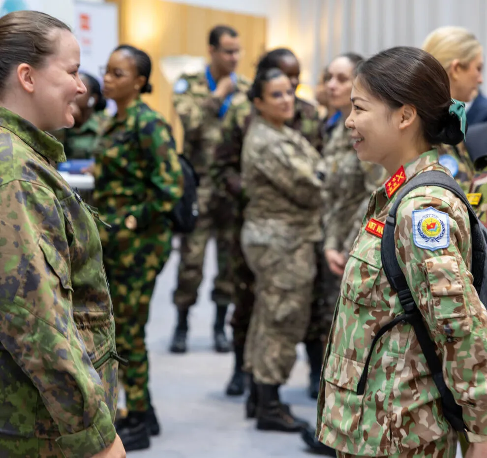 Several female peacekeepers in uniform, with two in the foreground smiling and talking.