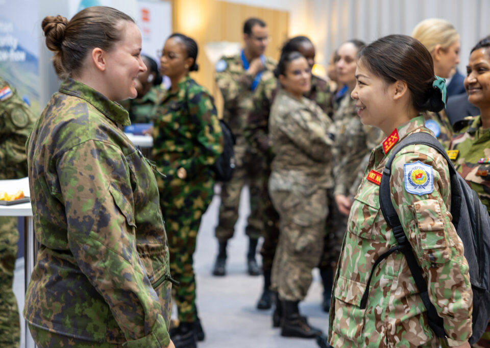 Several female peacekeepers in uniform, with two in the foreground smiling and talking.